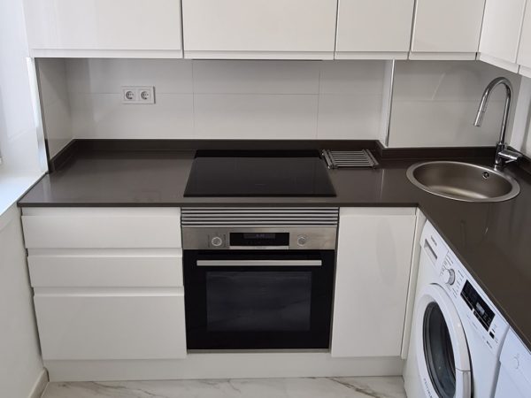 Cocina reformada con muebles blancos, horno y placa de inducción