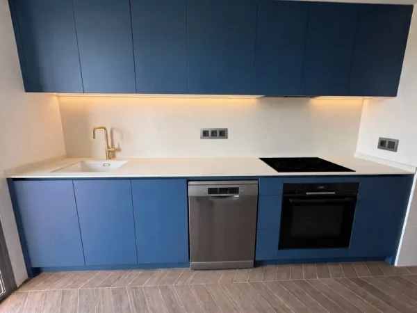 Cocina reformada en Leganés con muebles azules, encimera blanca y grifo dorado