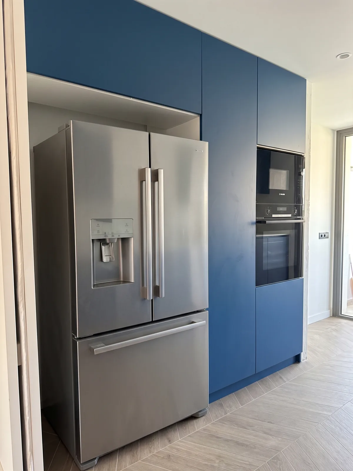 Nevera americana integrada en columnas azules en la cocina de Leganés